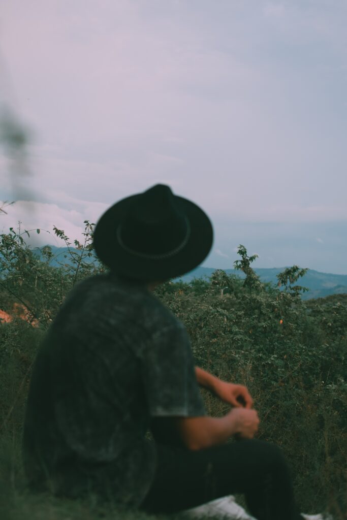 étudiant qui imprimer son mémoire sur papier recyclé avec formule éco responsable car il veut protéger la nature il porte un chapeau noir et regarde un paysage